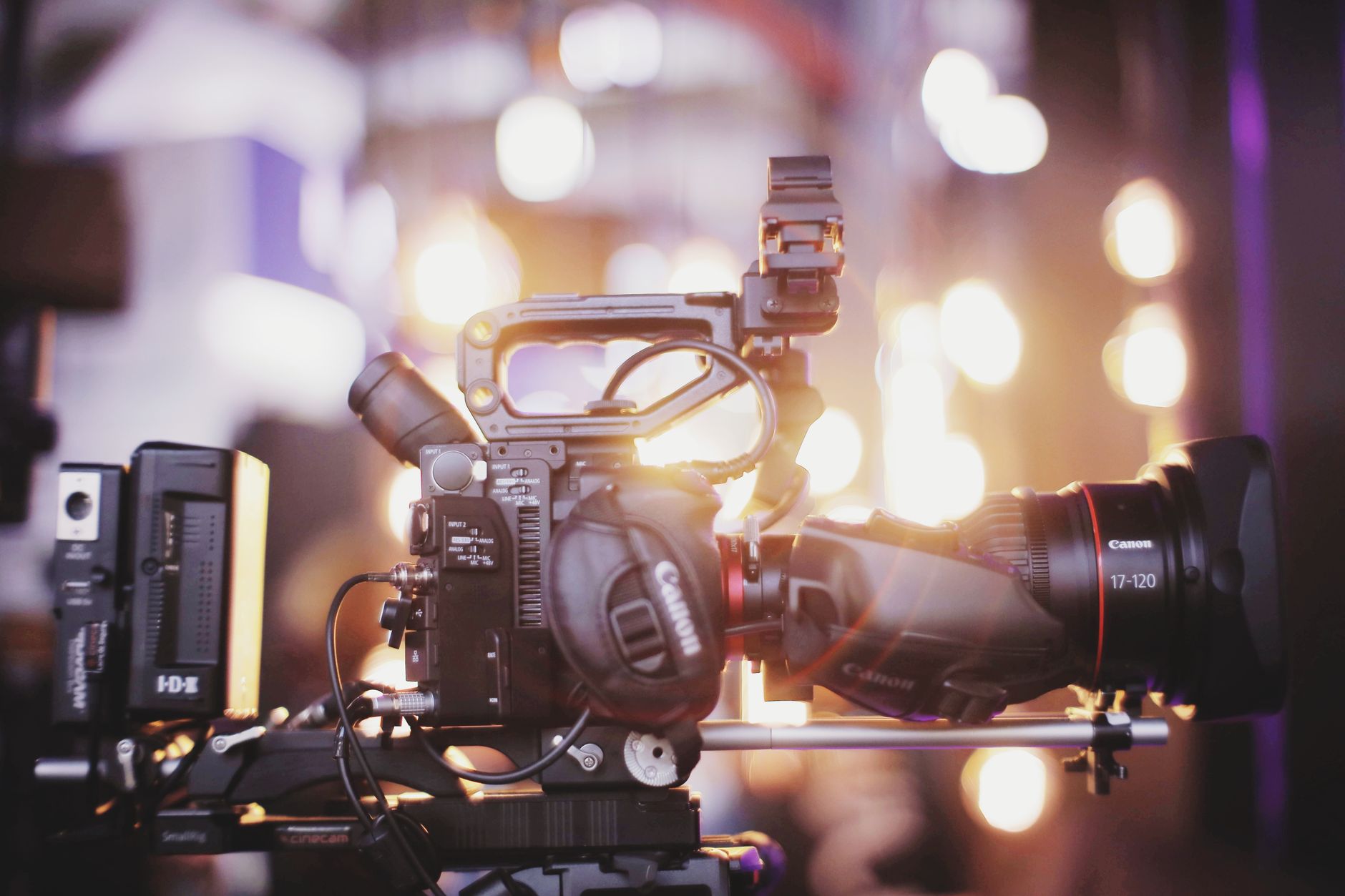 Gros plan sur une caméra de cinéma professionnelle avec un objectif de tournage devant des lumières floues.